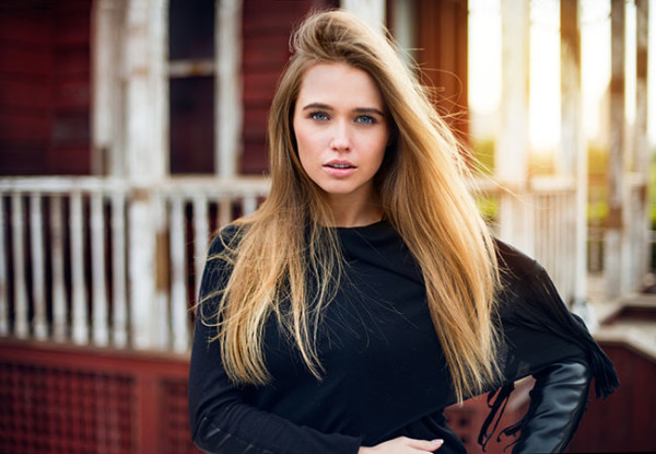 Beautiful blonde girl with long hair posing against old village